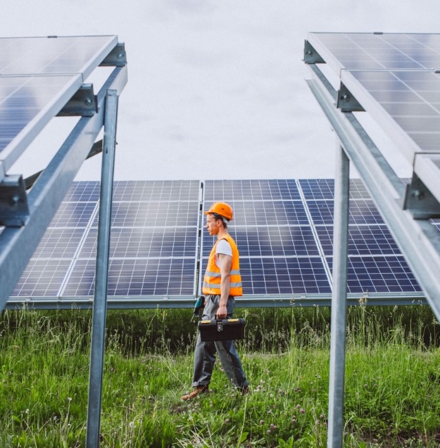 Técnico de SIENSOL caminando entre estructuras de paneles solares mientras realiza labores de inspección e instalación de soluciones fotovoltaicas para hogares, negocios e industrias.